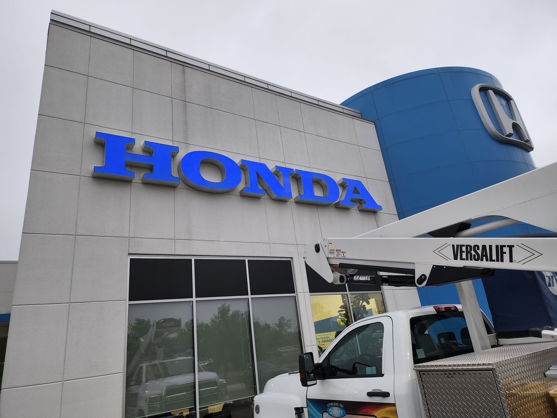 A white truck is parked in front of a honda dealership
