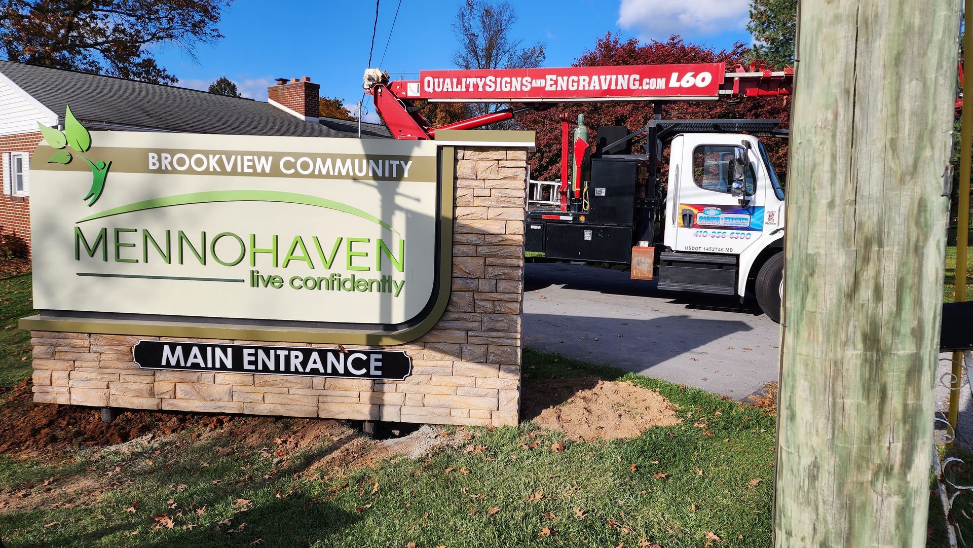 A white truck is parked in front of a sign that says main entrance.