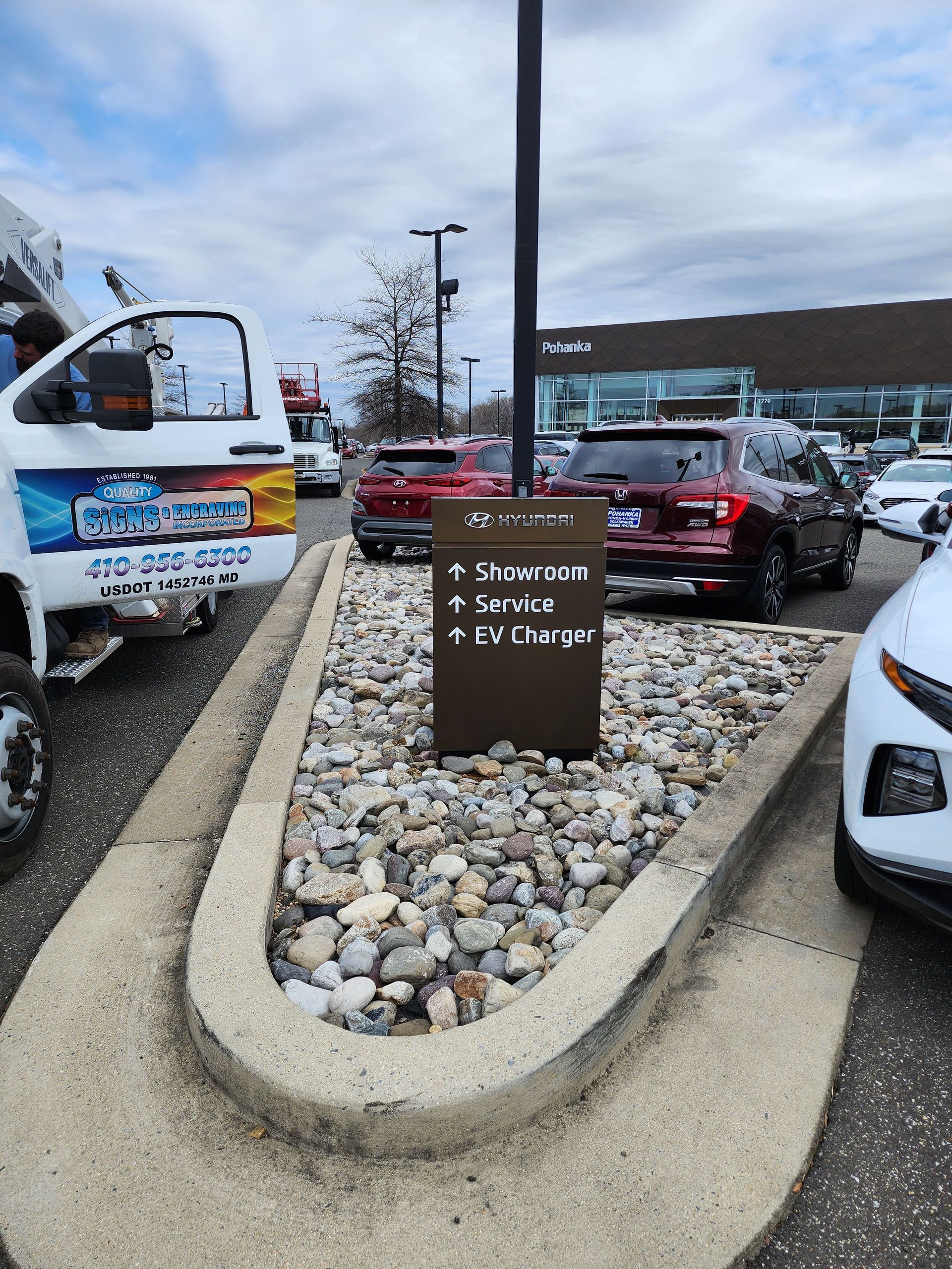 A white truck is parked next to a sign in a parking lot.