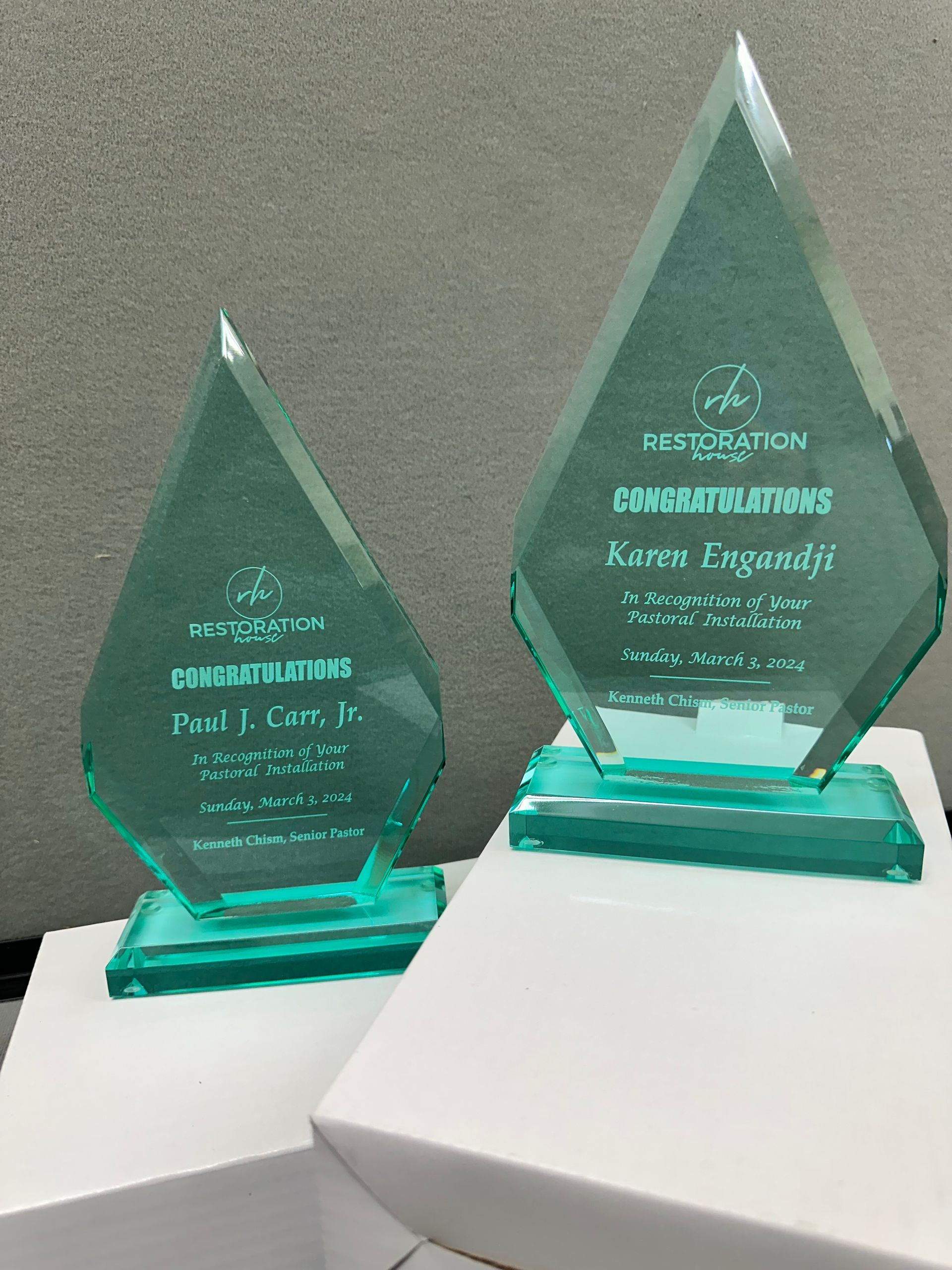 Two green glass trophies are sitting on top of white boxes.