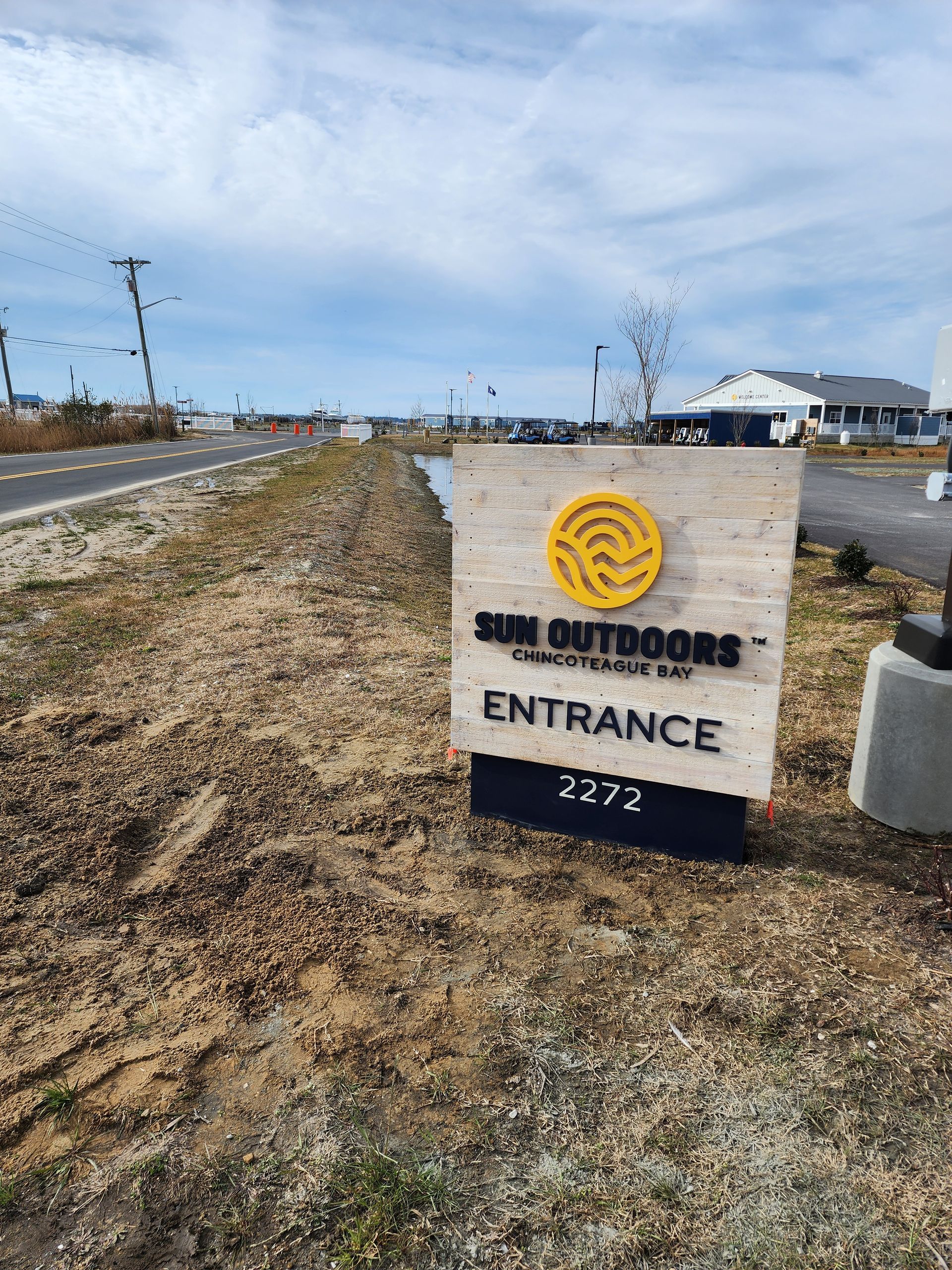 A sign that says `` entrance '' is sitting on the side of a dirt road.