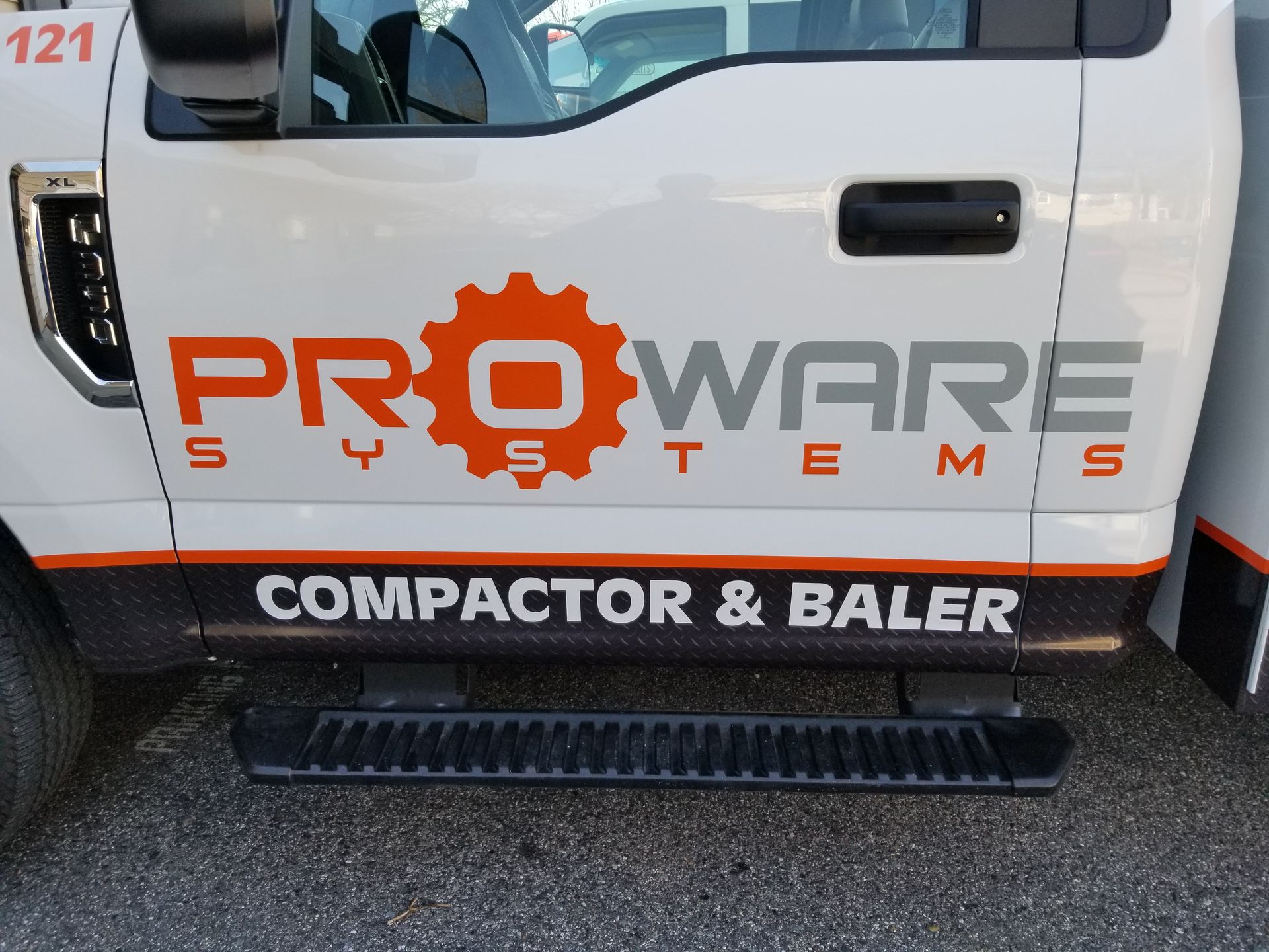 A white proware systems compactor and baler truck