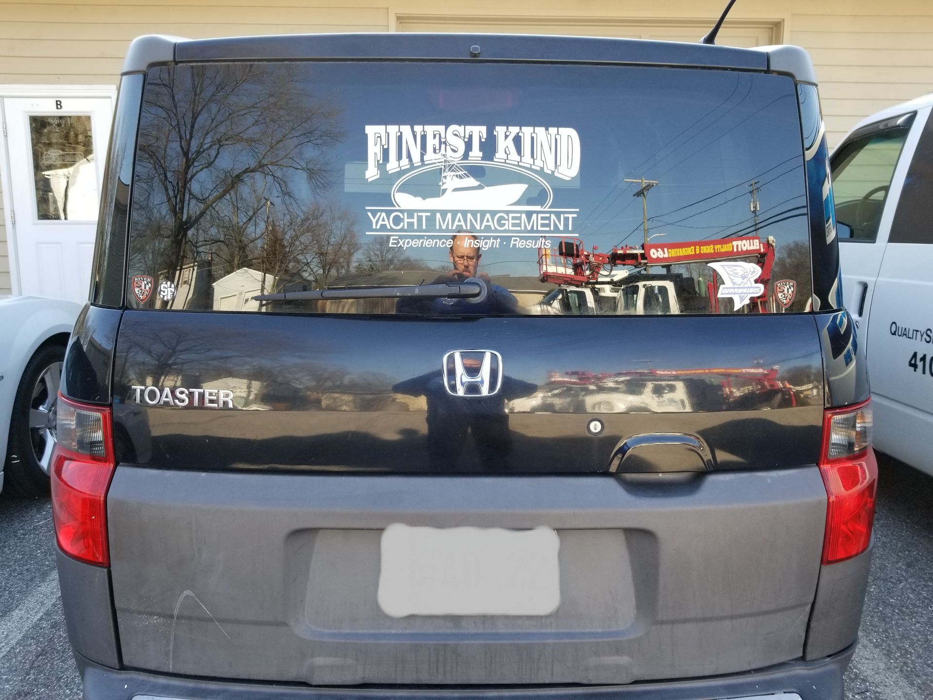 A black honda van with a sticker on the back window that says first kind