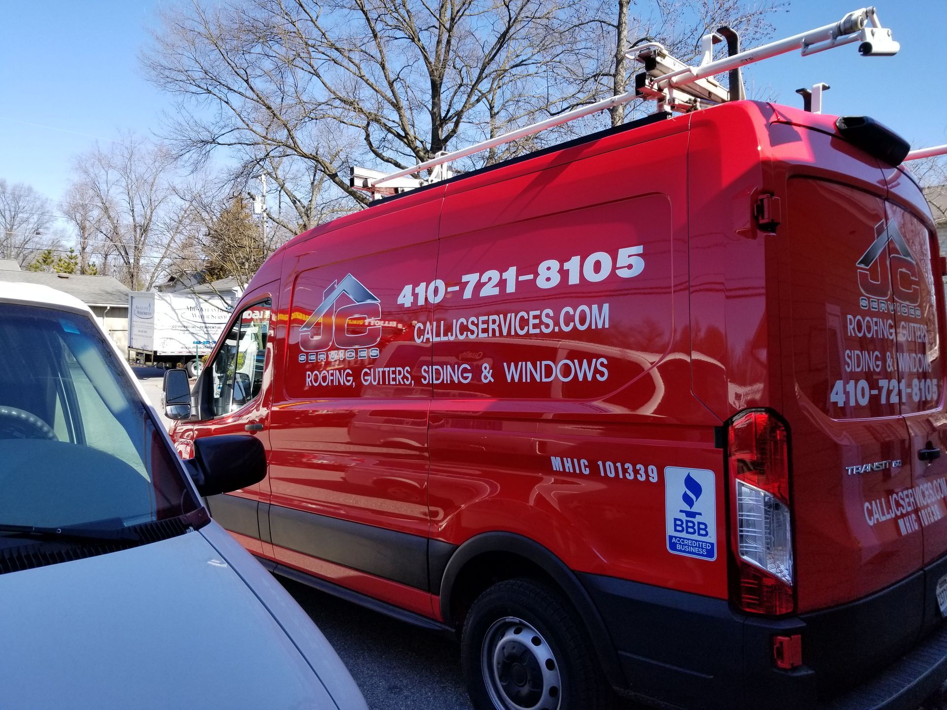 A red van is parked next to a white van.