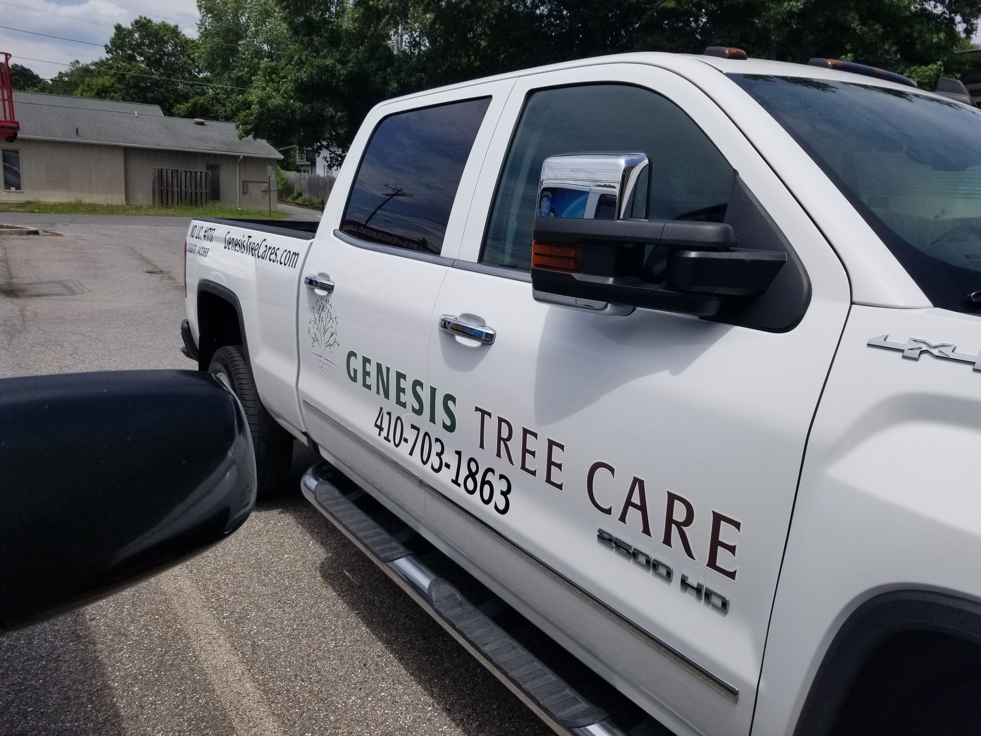 A white genesis tree care truck is parked in a parking lot