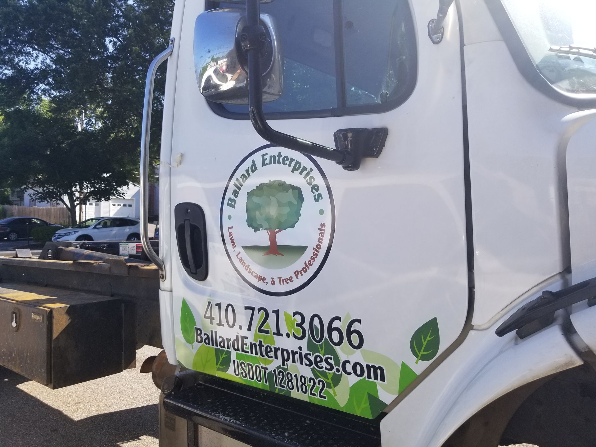 A white truck with a tree on the side of it