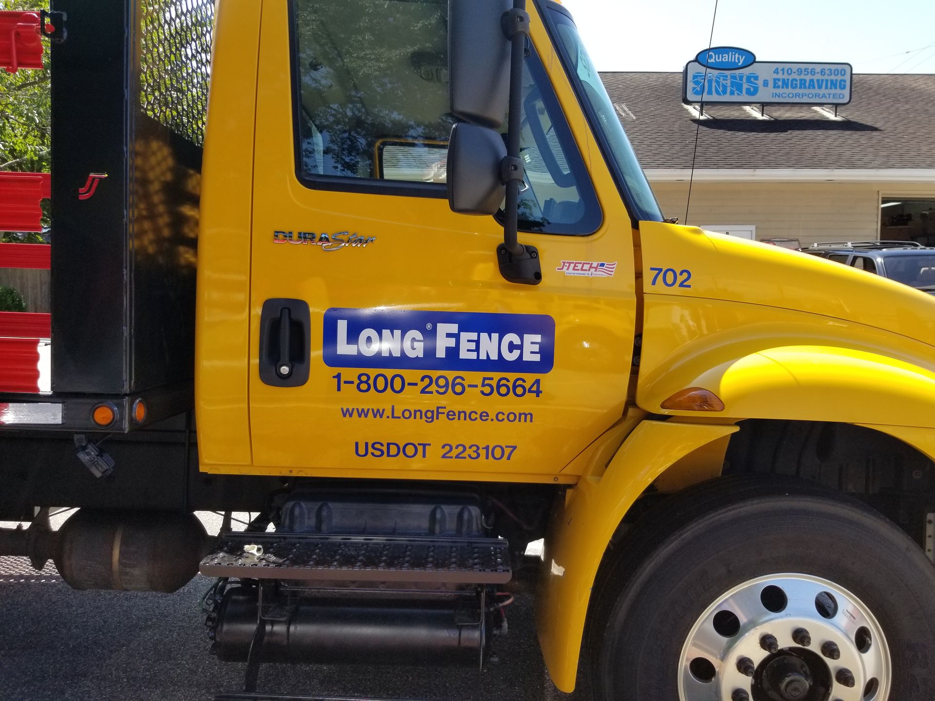 A yellow long fence truck is parked in front of a store