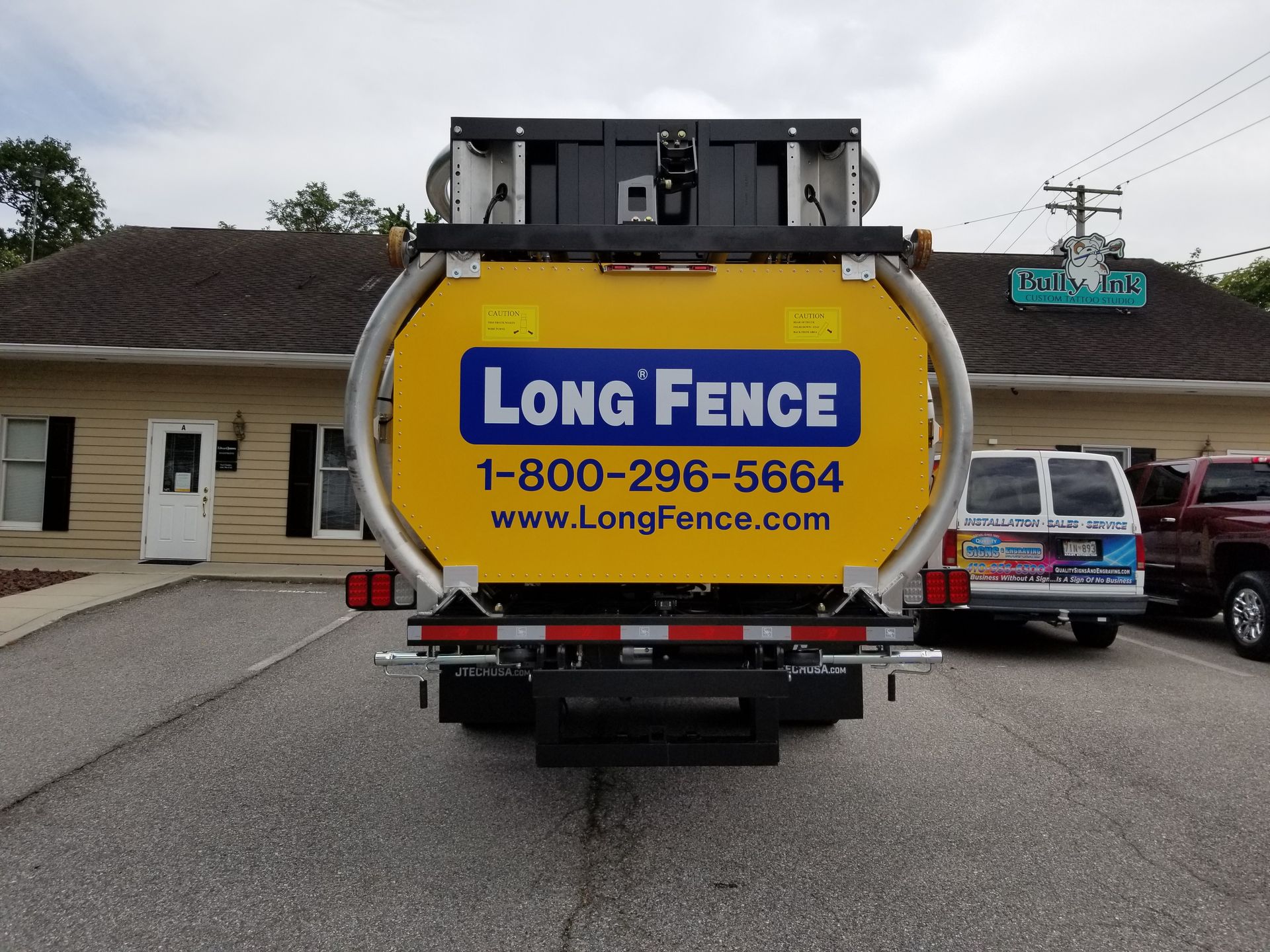A long fence truck is parked in front of a building