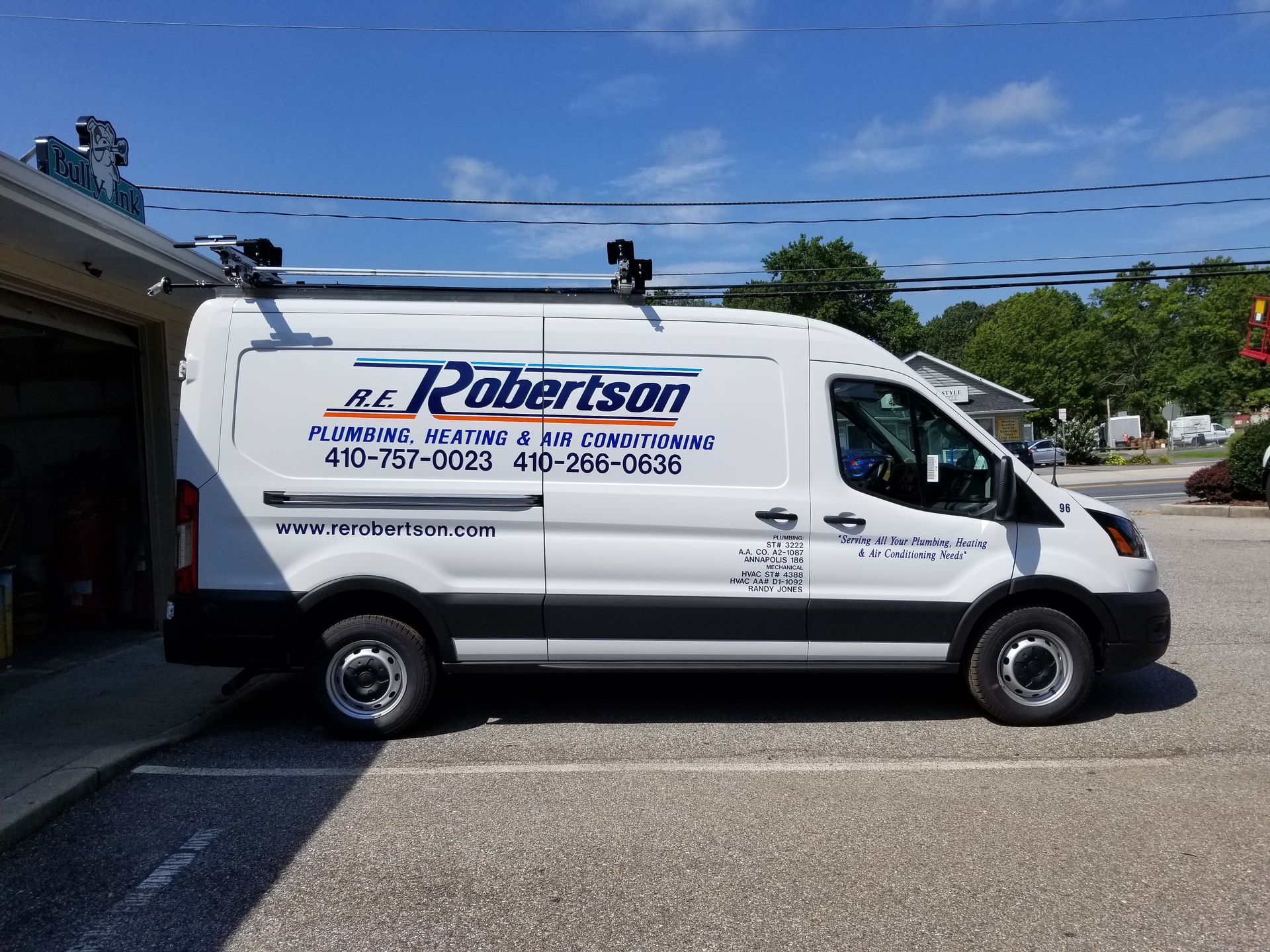 A white van is parked in a parking lot in front of a building.