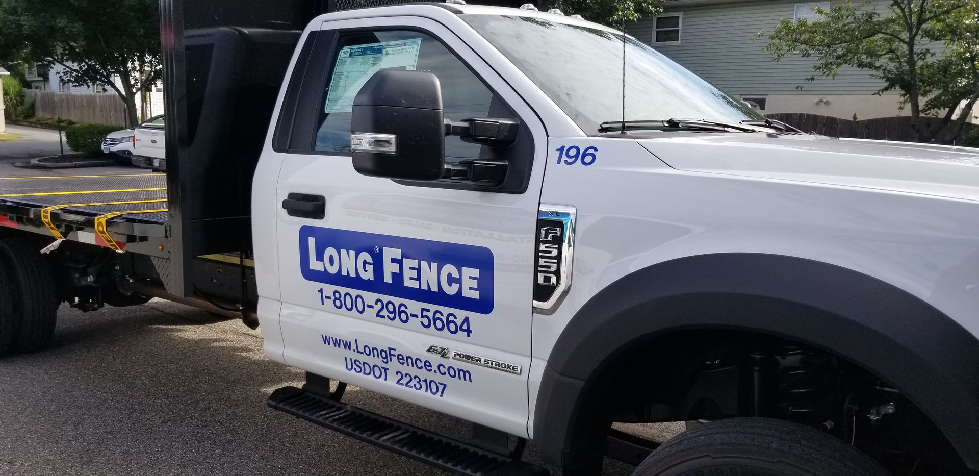 A long fence truck is parked on the side of the road.