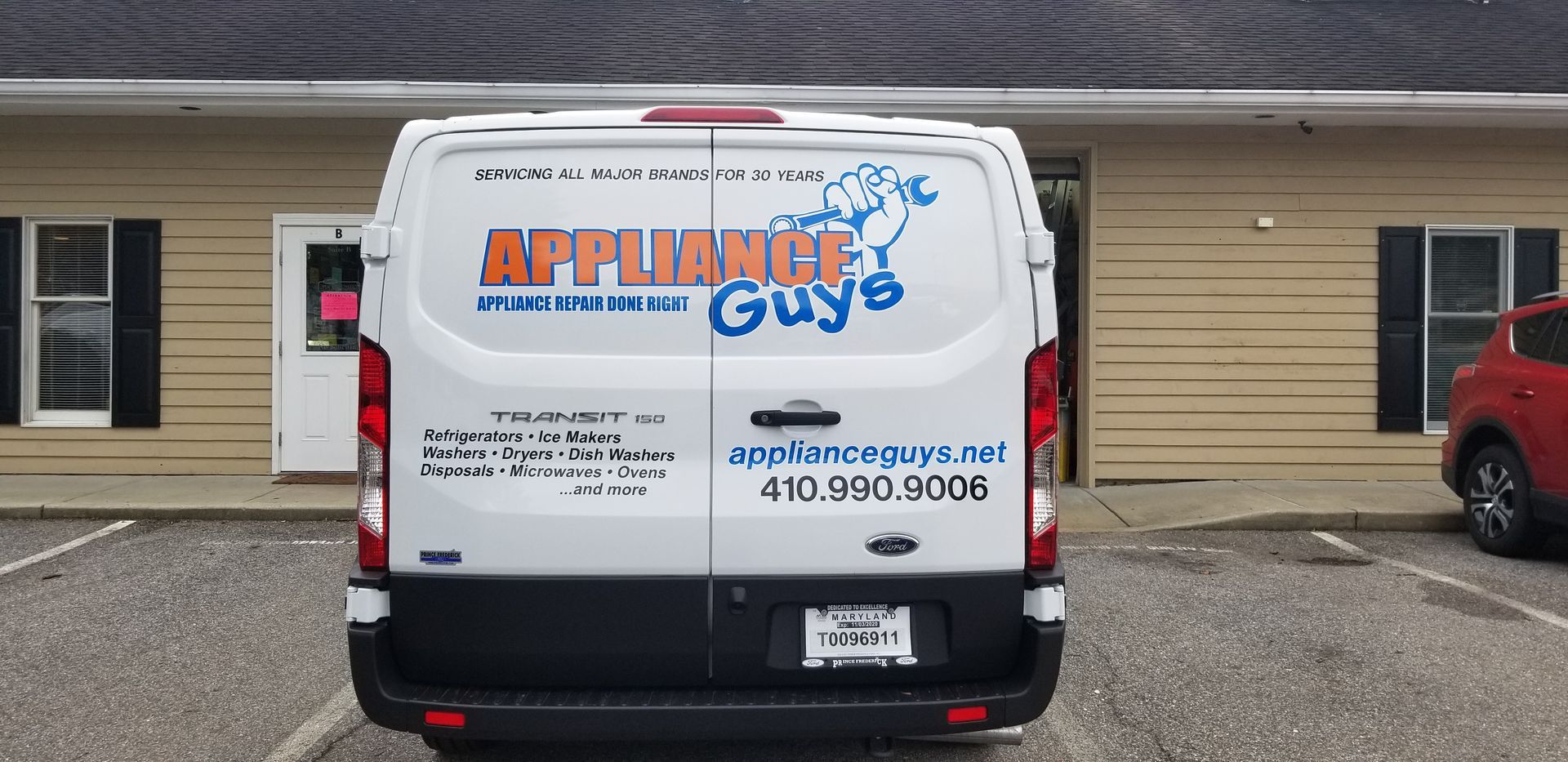 A white van with appliance guys written on the back is parked in front of a building.