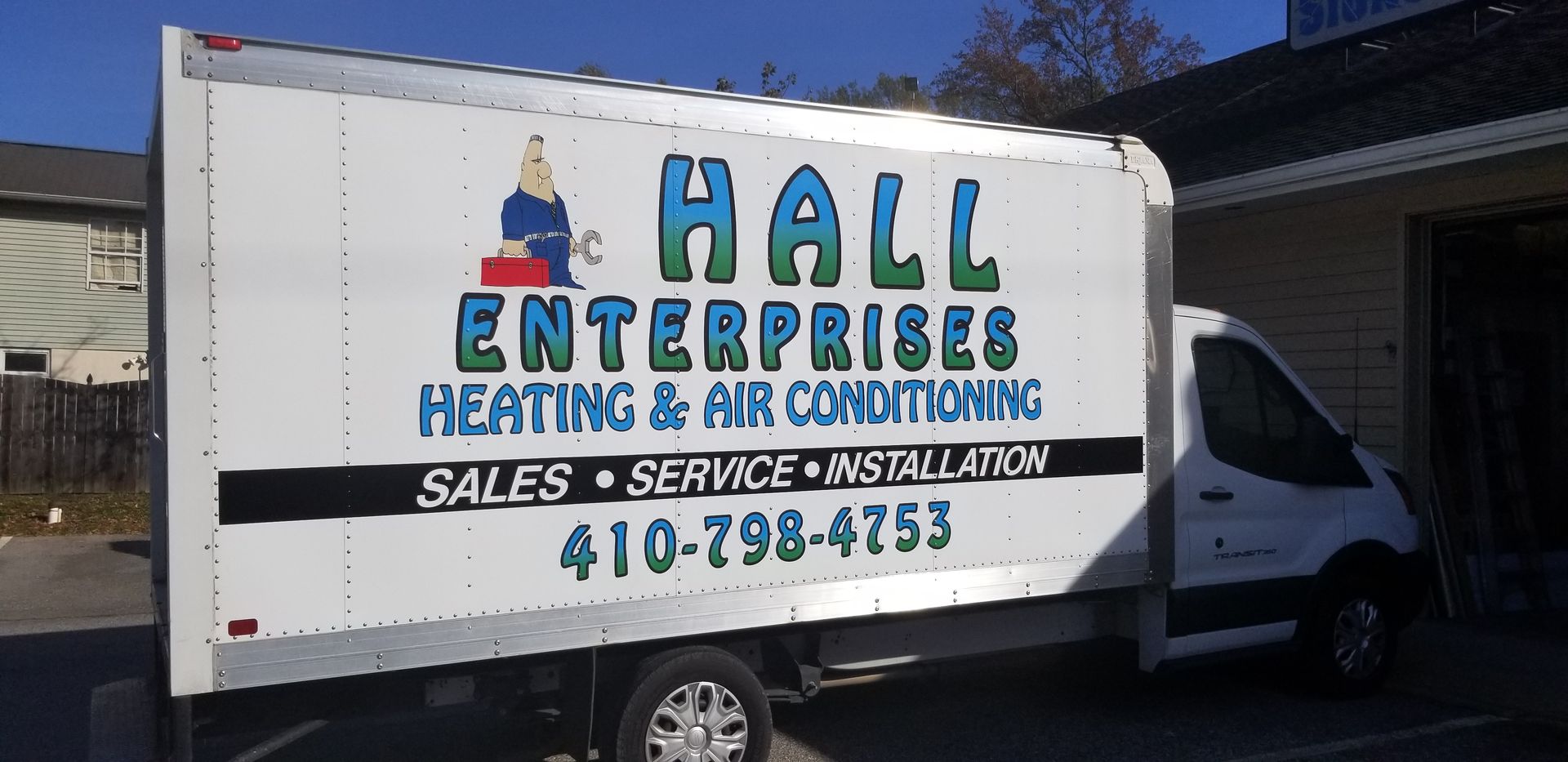 A hall enterprises heating and air conditioning truck is parked in front of a building