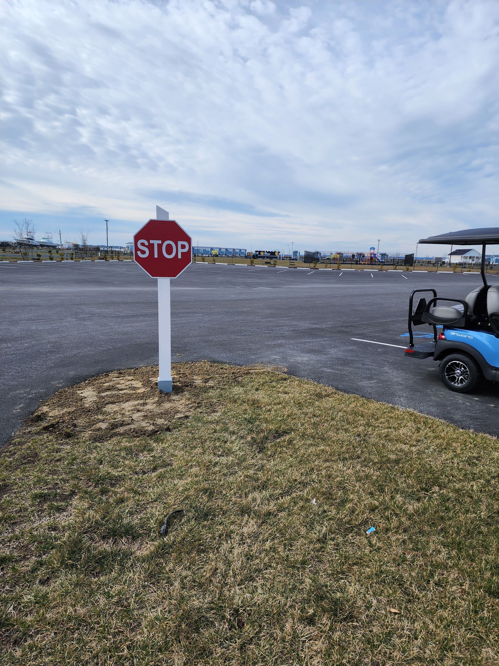 A stop sign in a parking lot next to a golf cart