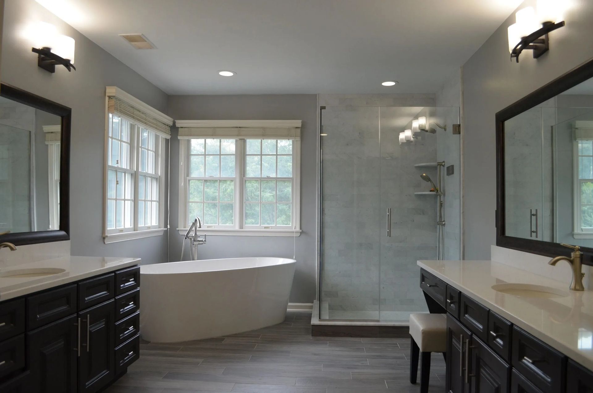 Spacious modern bathroom with a soaking tub, glass shower, and dark wood vanities.