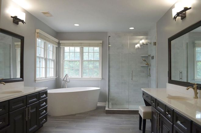 A modern bathroom with a tub, shower, and double vanity in shades of gray, white, and black.