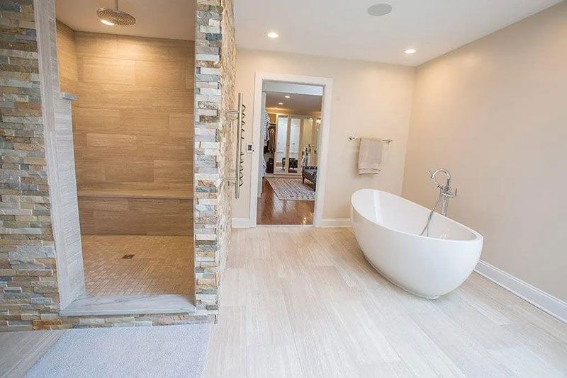 Modern bathroom with stone shower, soaking tub, and light wood floors.