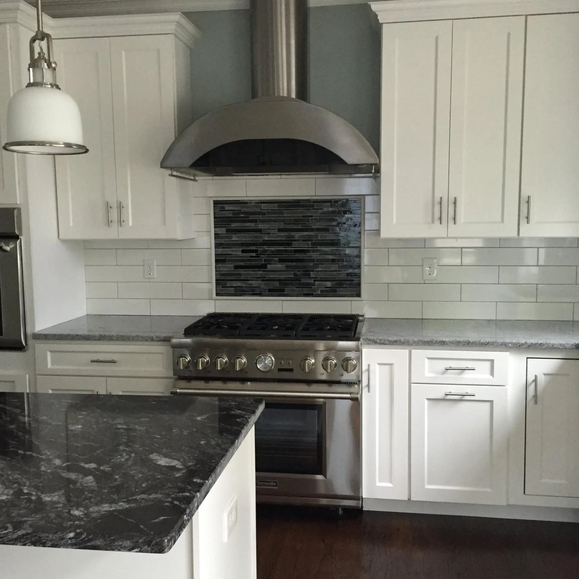 Kitchen with white cabinets, stainless steel appliances, and dark granite countertops.
