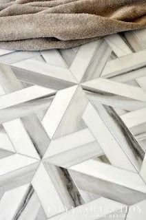 Geometric white and gray marble tile floor, with a neutral-toned blanket partially visible in the top.