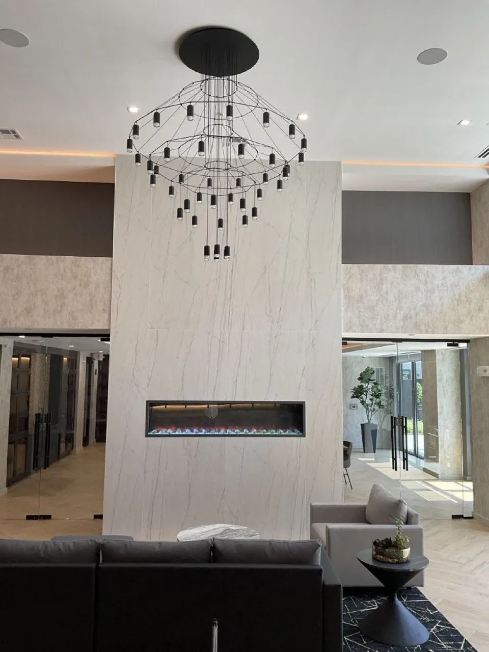 Modern lobby with fireplace, large light fixture, and seating area.