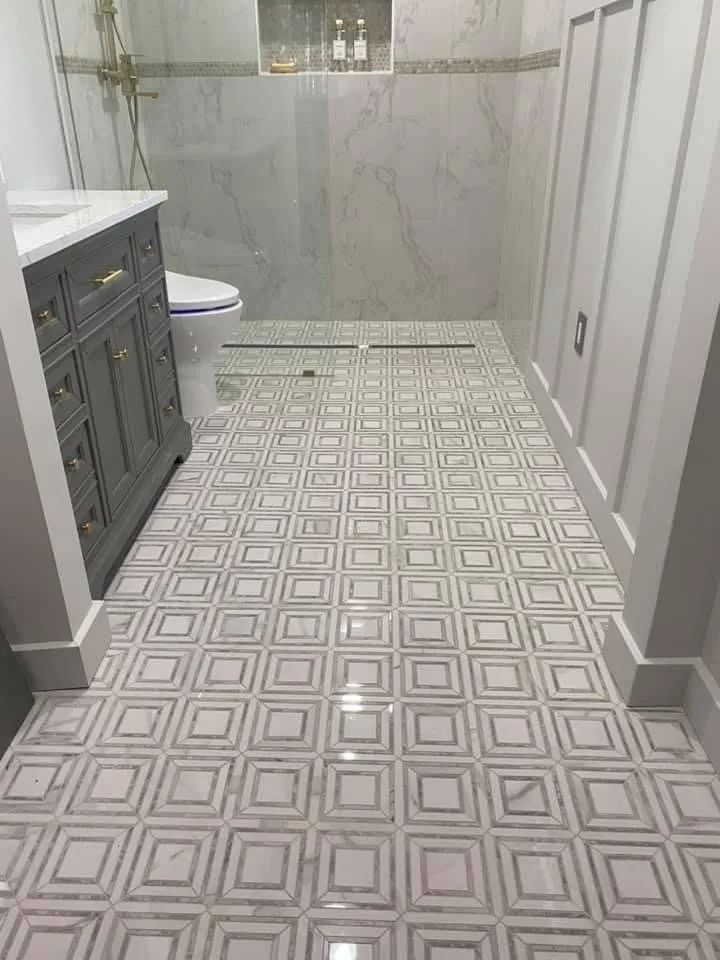 Bathroom with gray vanity, patterned tile floor, and marble shower.