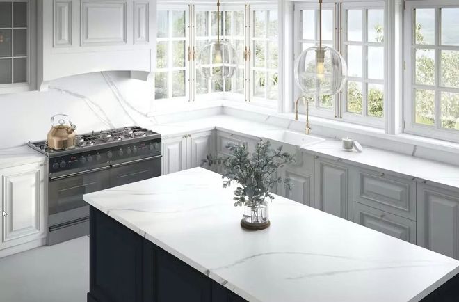 U-shaped kitchen with white marble countertops, gray cabinets, and a dark blue island. Windows offer a bright view.