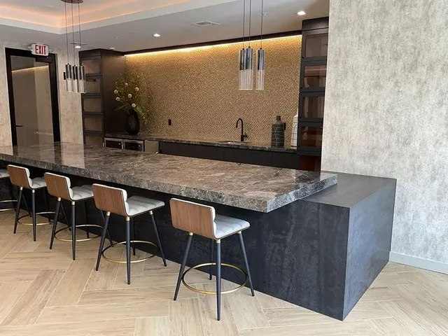 Bar area with seating, dark countertops, beige mosaic backsplash, and pendant lights.