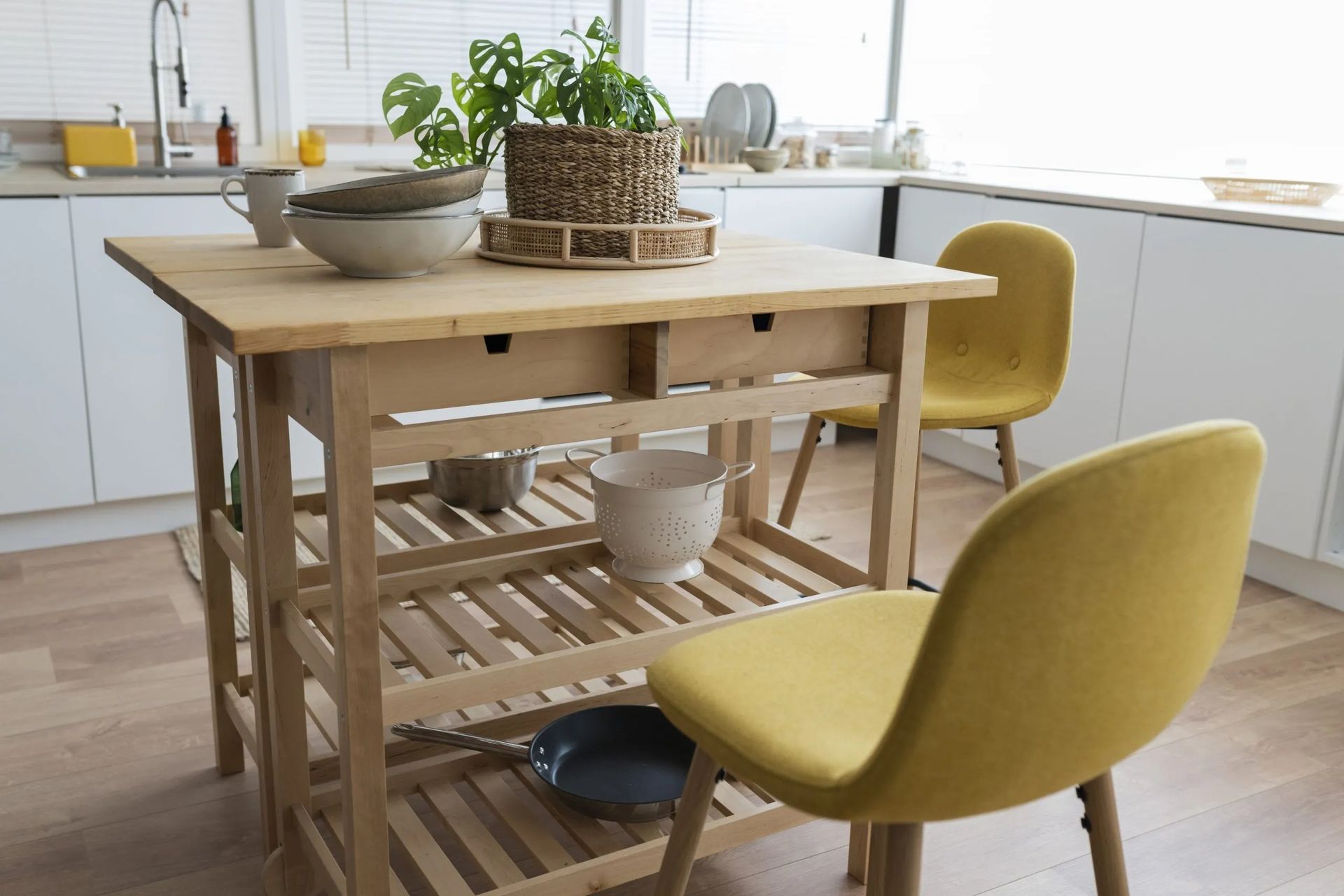 Kitchen island with wooden frame, two yellow chairs, and potted plant.