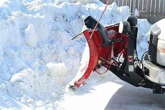 Red snowblower on a truck clearing snow on a sunny day.
