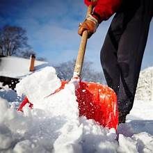 Person shoveling snow with red shovel on a snowy day.