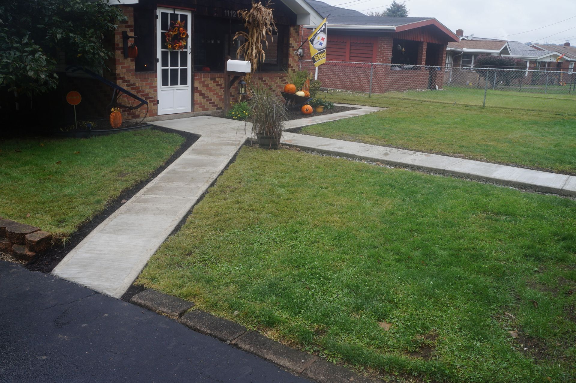 Concrete pathway leading to a brick house with Halloween decorations on the lawn.