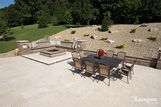 Patio with dining set, fire pit, and seating area overlooking a sloped, landscaped yard.