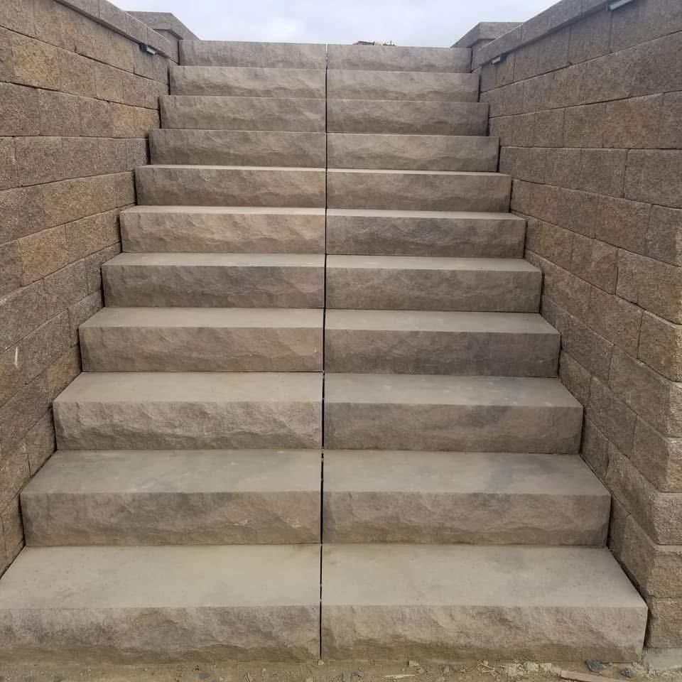 Stone steps leading upwards, flanked by matching stone walls, under a cloudy sky.