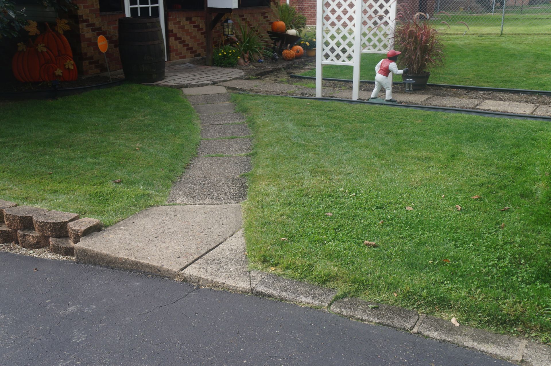 Child in costume runs on a sidewalk towards a white trellis in a grassy yard.