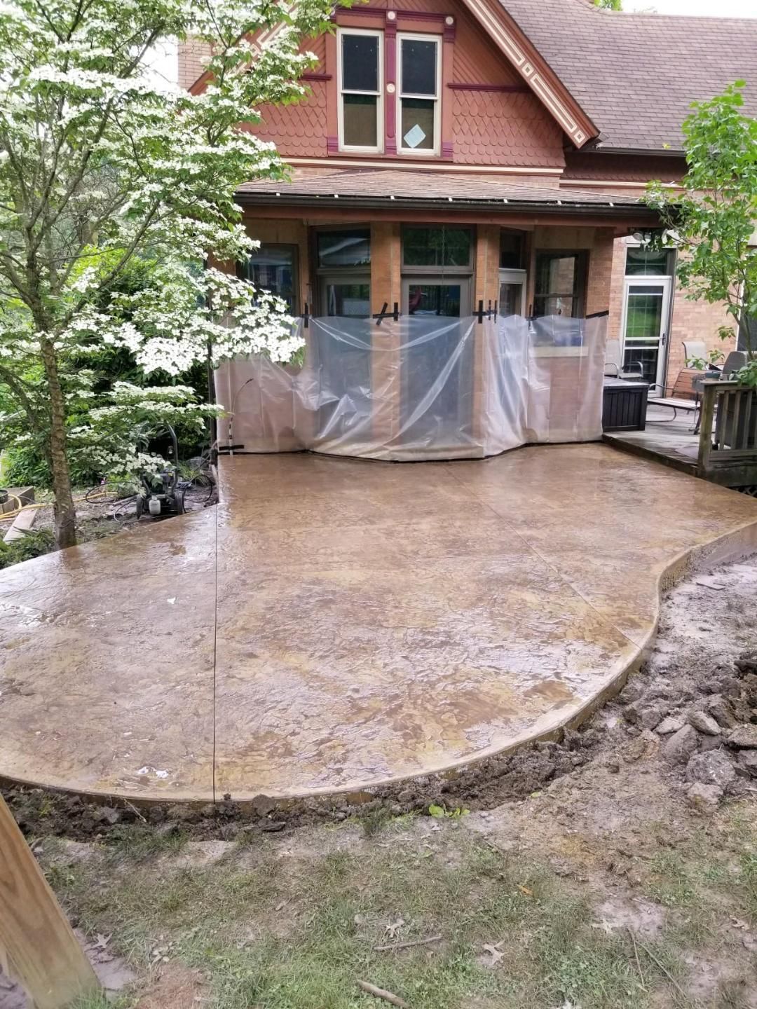 Wet concrete patio in front of a brick house, still under construction.