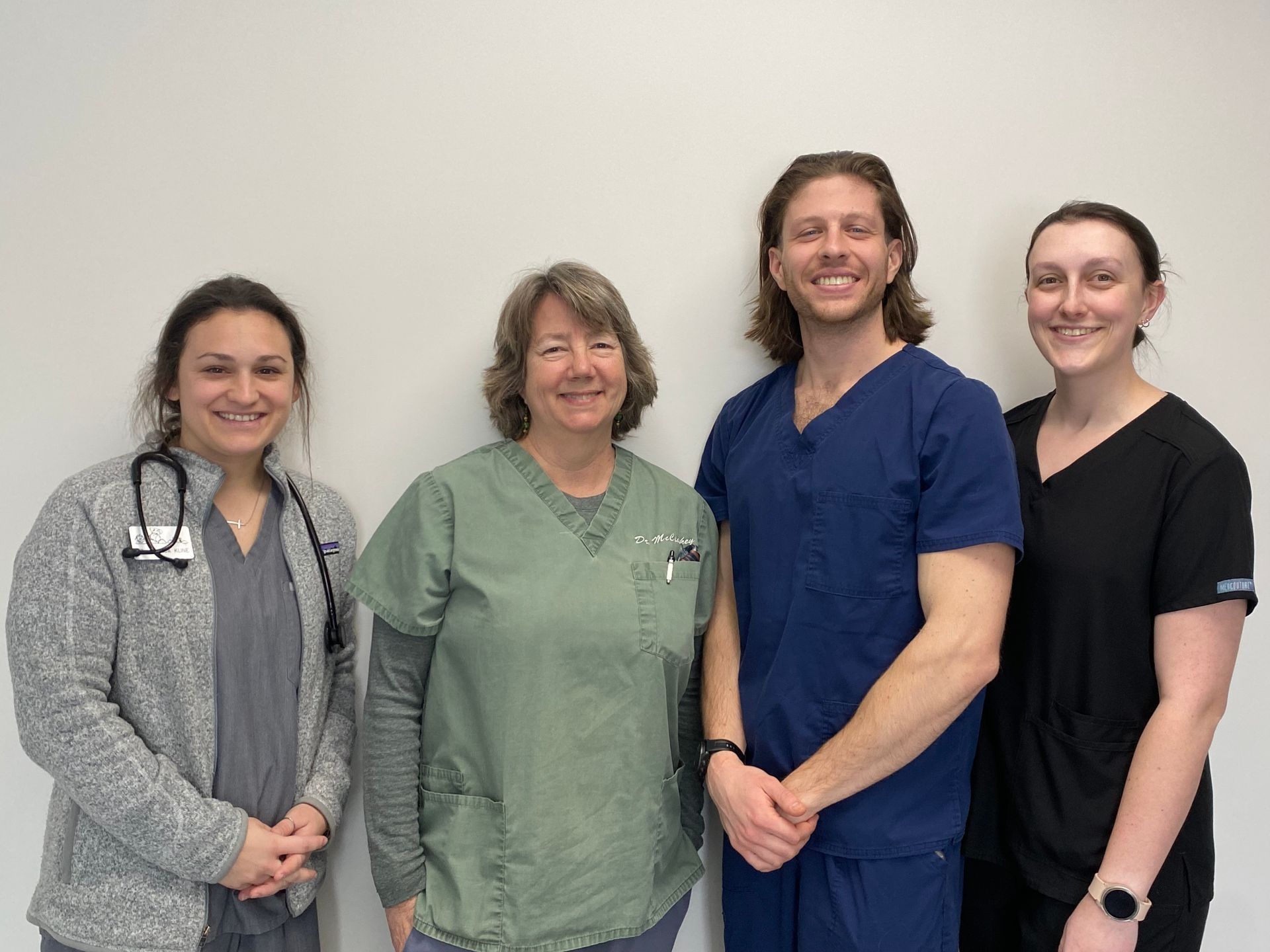 Dog and tabby cat peering over a white surface. Dog is tan, cat is brown and gray.