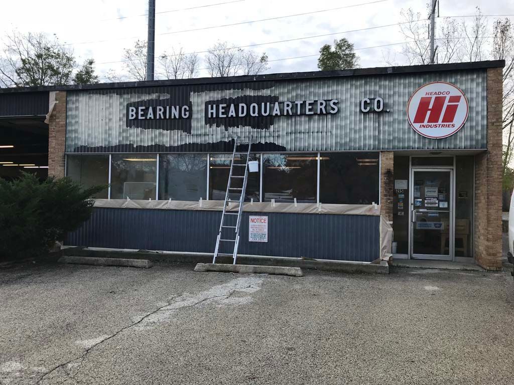 Small industrial storefront with “Bearing Headquarters Co.” sign and ladder in front