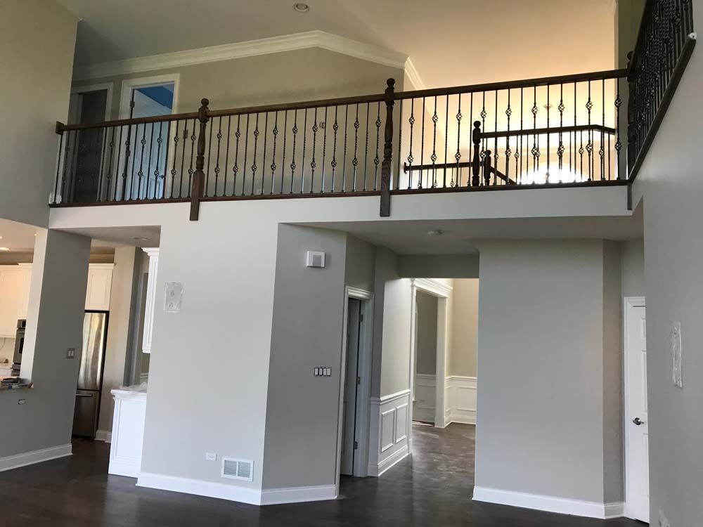 Open loft living room with vaulted ceiling, dark railing, and doorways below the upstairs balcony.