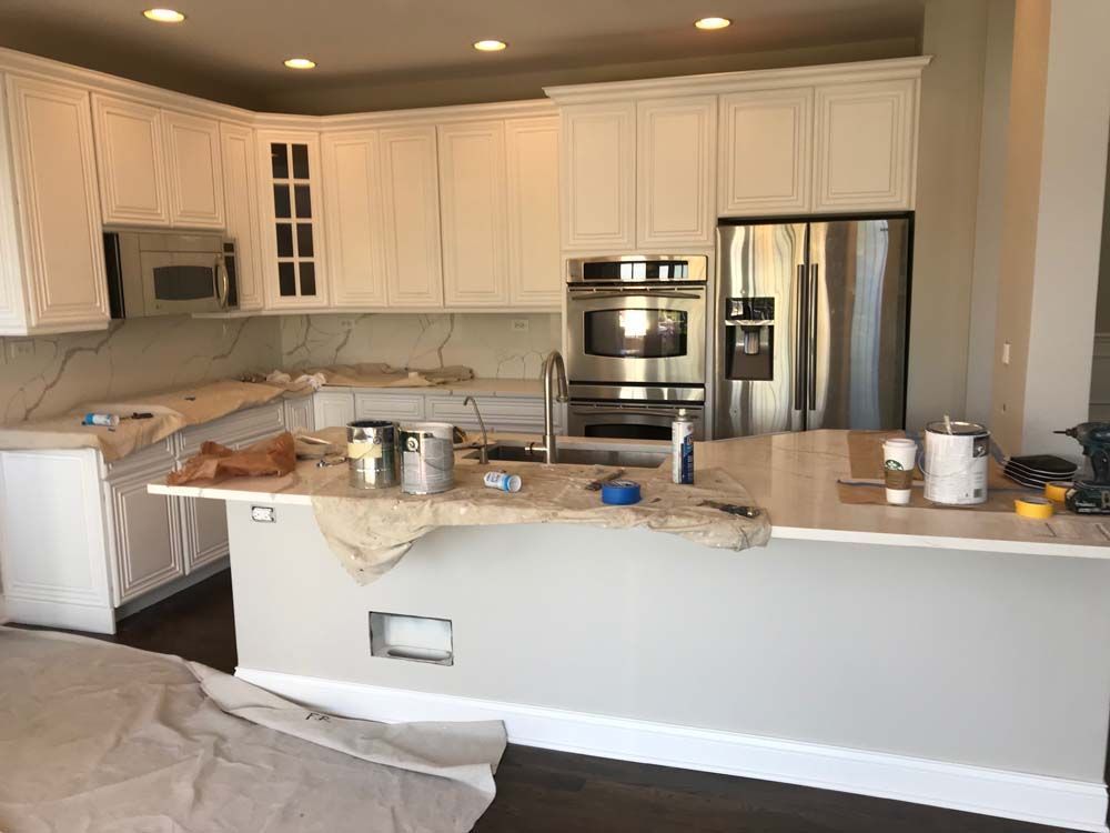 Modern white kitchen with stainless appliances, granite island, and cabinets under recessed lighting