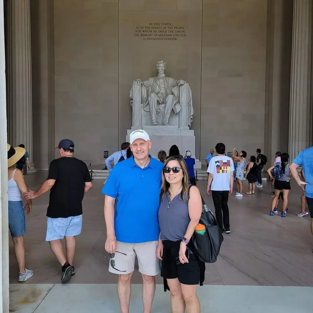 Couple posing inside a grand memorial hall in front of a large seated statue