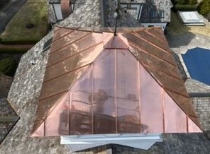 Copper-colored roof over a building with a central skylight, viewed from above