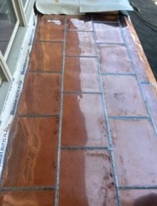 Wet terracotta tile floor with a reflective patch near a doorway