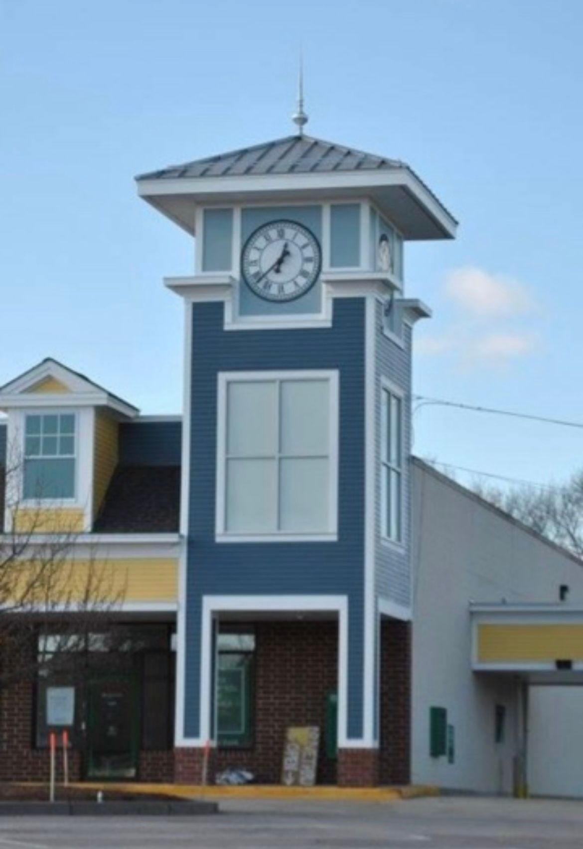 Clock tower on a blue-and-white building with a peaked roof under a clear sky