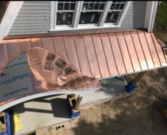 Copper standing-seam roof being installed on a house with exposed underlayment and scaffolding below.