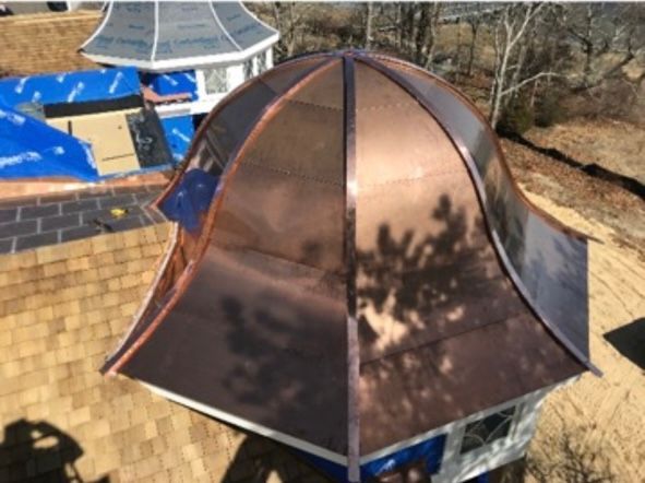 Copper-colored roof on a small gazebo with a pointed top, seen from above outdoors