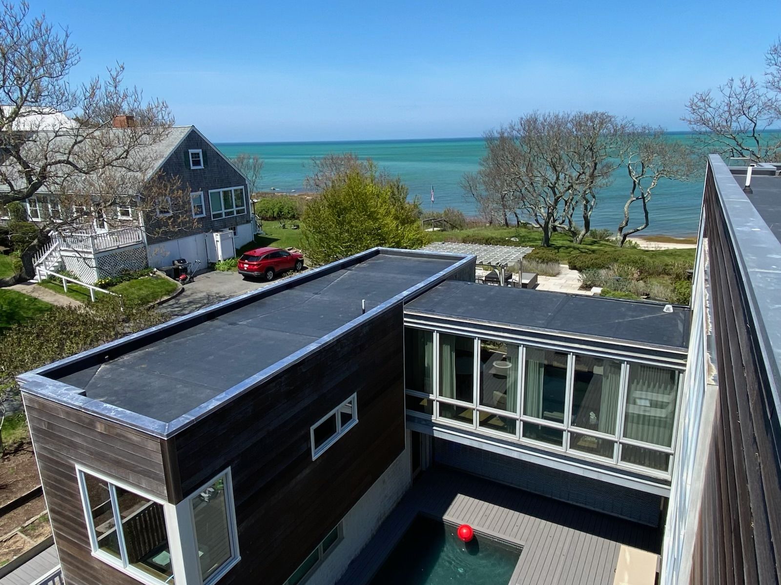 Coastal house rooftops overlooking turquoise sea under a clear blue sky
