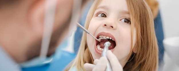 dentist examining a small girl's teeth