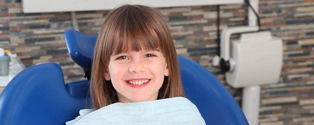 smiling child patient sitting at dentist office