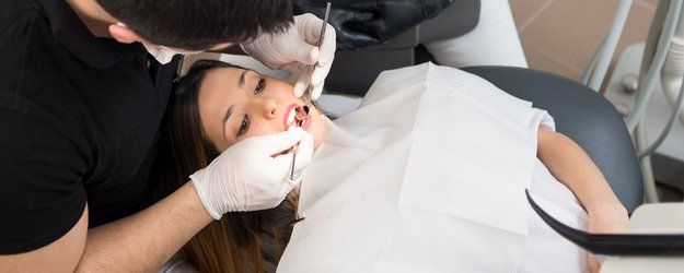 Male dentist treating patient teeth