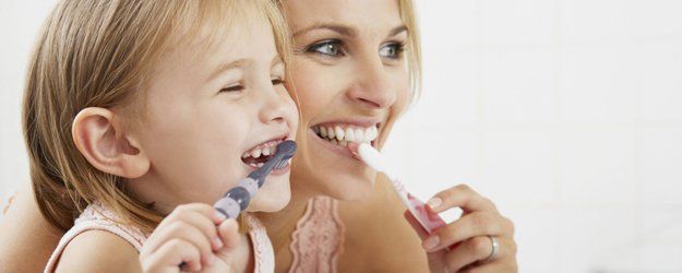 mother and daughter brushing teeth together