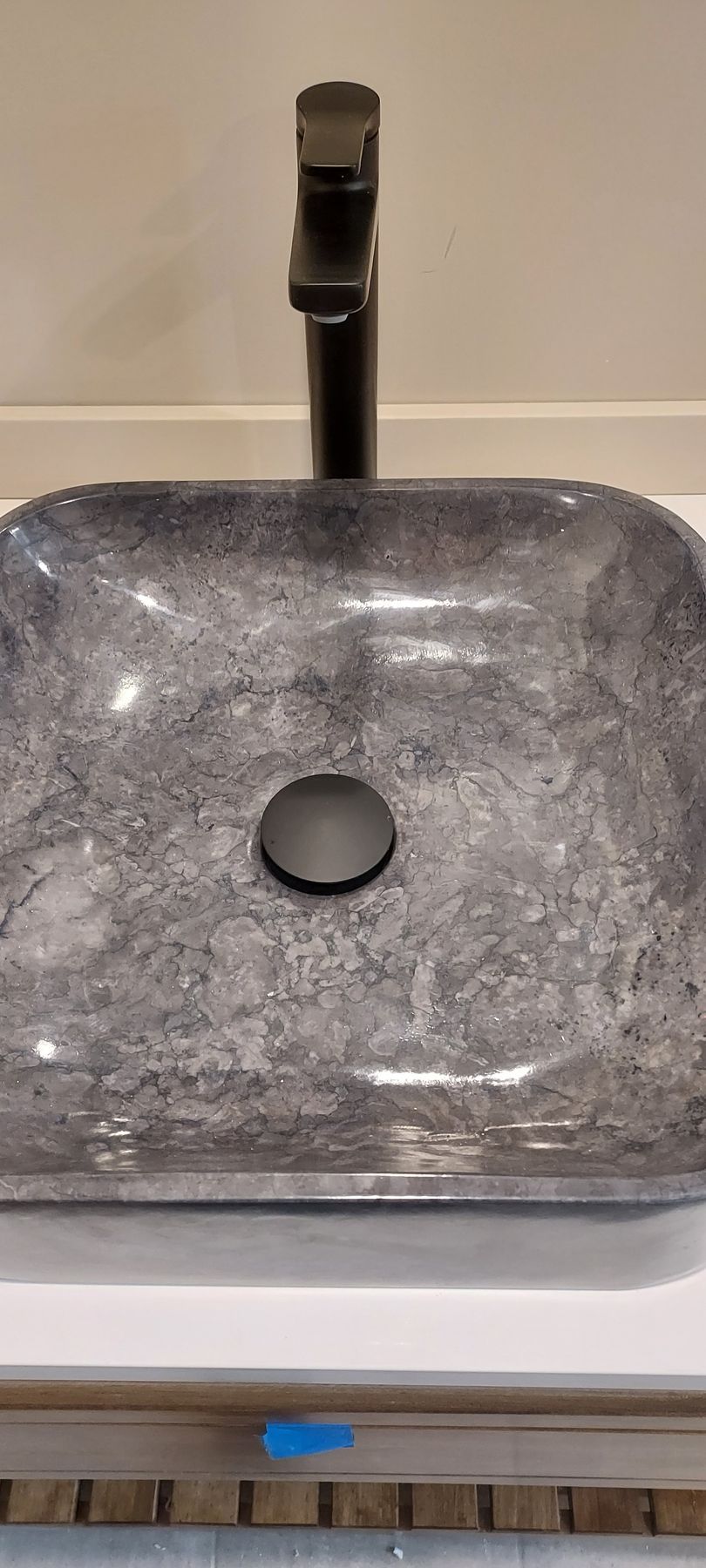 Gray square bathroom sink with a chrome faucet and drain.